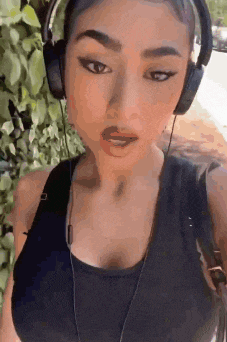 a woman wearing headphones is taking a selfie while walking down the street .