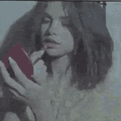 a woman is holding a red bottle of perfume in her hand and licking it .
