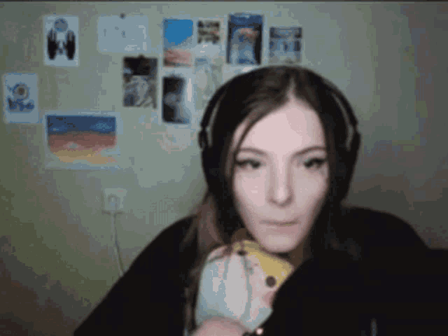 a girl wearing headphones looks at the camera while holding a stuffed animal