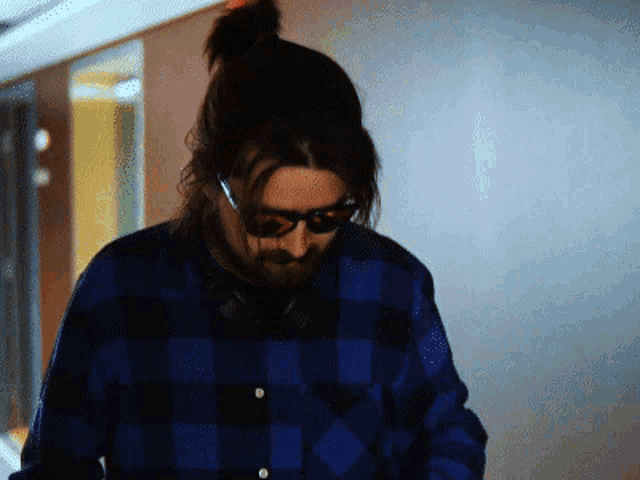 a man wearing a plaid shirt and headphones looks down