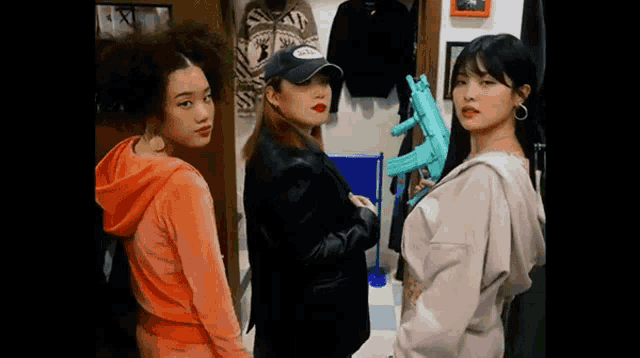 three women are standing next to each other in a room holding guns .
