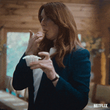 a woman is eating a cupcake with a netflix logo in the background
