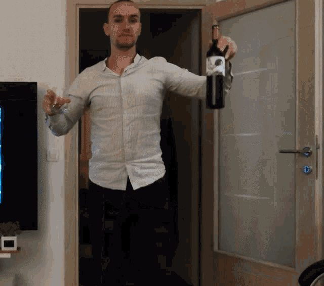 a man in a white shirt is holding a bottle of wine and a glass of wine