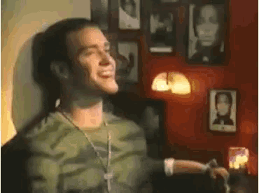a man in a camouflage shirt is smiling in front of a wall with pictures on it .