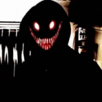 a person in a black hoodie with red eyes and teeth .