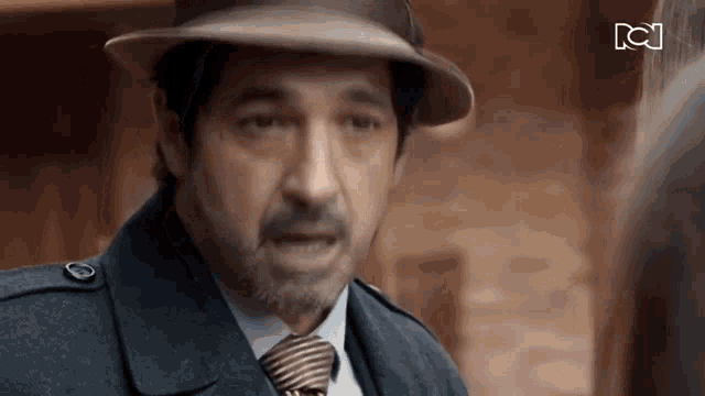 a man wearing a hat and tie is talking to another man