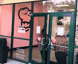 a woman is standing in front of a store that says taste weekly