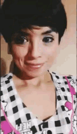 a woman with short black hair is wearing a hello kitty shirt and making a funny face .