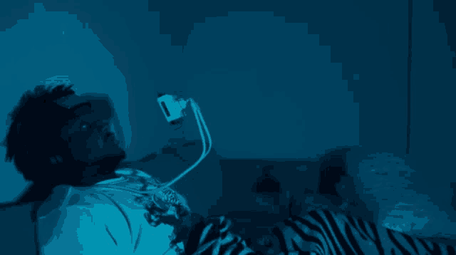 a man in a white shirt with a tiger on it is laying in a bed