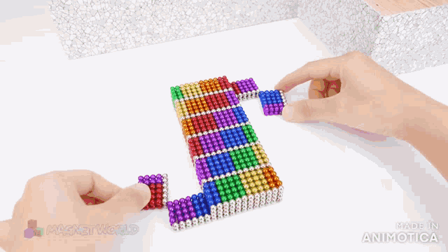 a person is playing with a rainbow colored magnet world toy