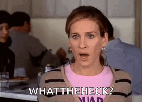 a woman is sitting at a table with her mouth open and the words `` what theheck '' written on her face .