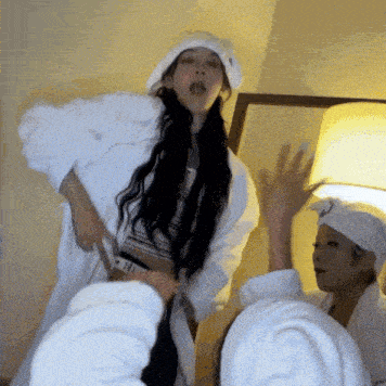 a woman in a white robe is standing in a room with other women