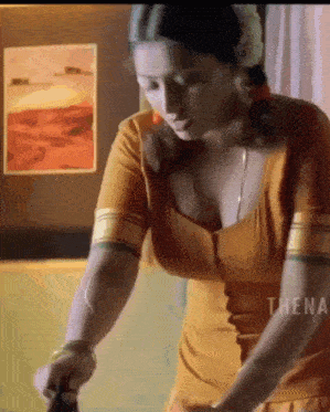 a woman in a yellow top is standing in front of a wall with a picture on it that says thena