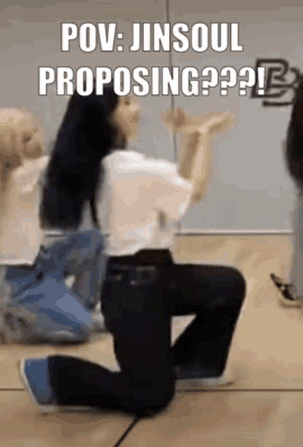 a woman is kneeling down on the floor with her hands in the air while a group of people are dancing in a room .