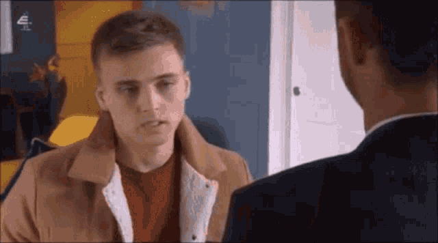a man in a suit is talking to another man in a room .