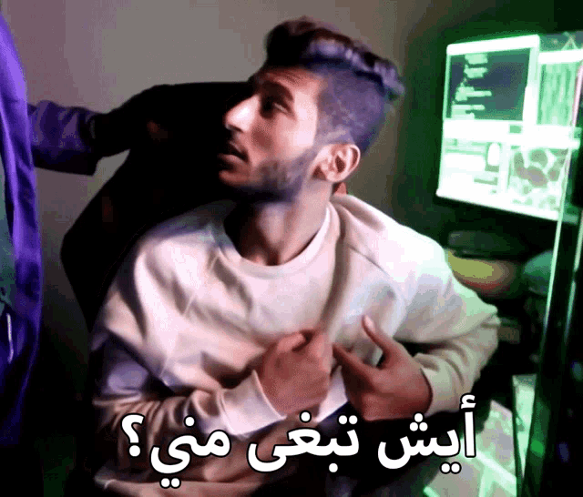 a man sitting in front of a computer with arabic writing