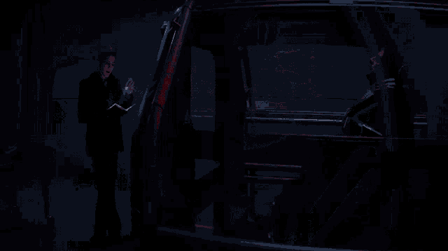 a man is holding a flashlight in his hand while looking out of a car window .