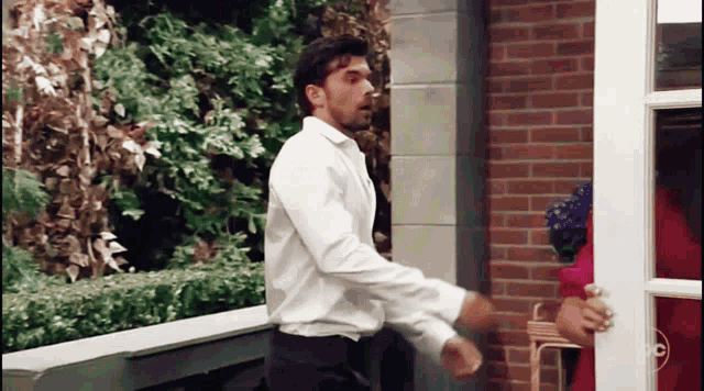 a man in a white shirt opens a door