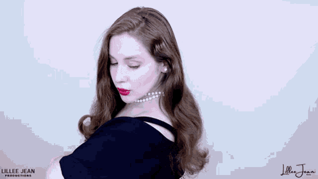 a woman in a black dress with red lipstick is looking over her shoulder .