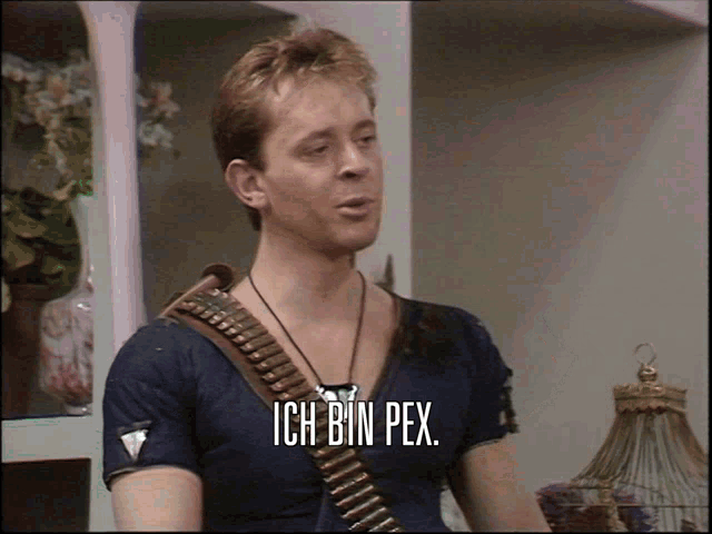 a man in a blue shirt with a belt around his neck says ich bin pex