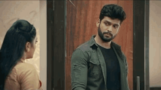 a man with a beard and a woman are standing next to each other in front of a door .
