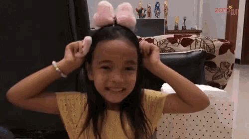 a little girl wearing a headband with a pink bow on it and the word zor on the bottom