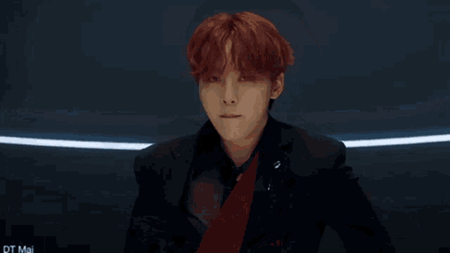 a young man with red hair is wearing a black suit and a red shirt .