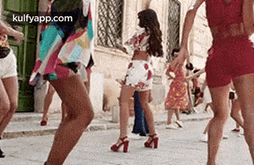 a group of women are dancing in a street .