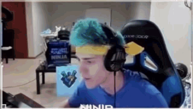 a man with blue hair is wearing headphones and a yellow headband .