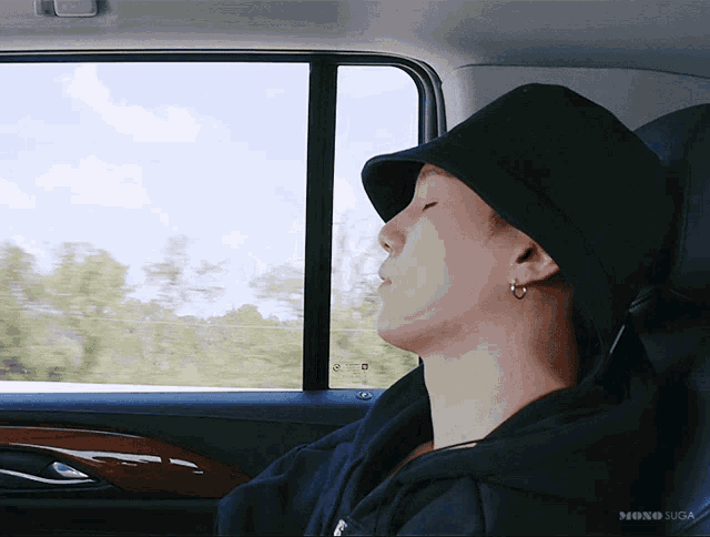 a man wearing a black hat sleeping in a car