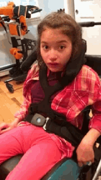 a girl in a wheelchair with a black belt around her neck