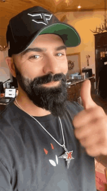 a man with a beard wearing a hat and giving a thumbs up sign