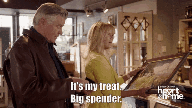 a man and a woman are looking at a framed picture with the words it 's my treat big spender