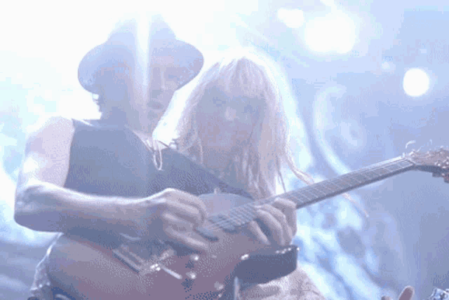 a man playing a guitar next to a woman with pink hair