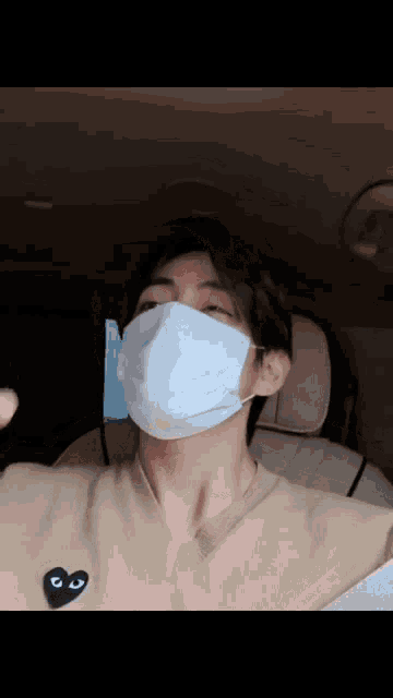 a man wearing a white face mask is sitting in a car ..