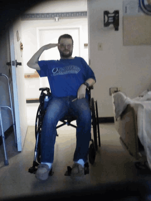 a man in a wheelchair salutes while wearing a shirt that says ' oakland raiders ' on it