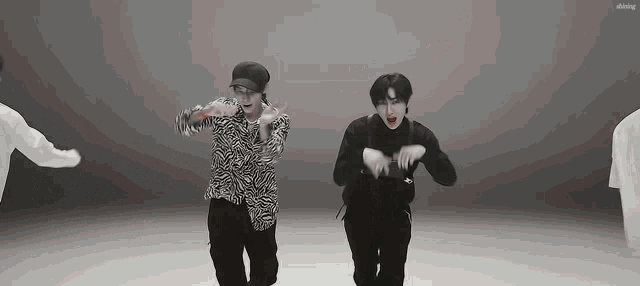 a group of young men are dancing together on a stage in a black and white photo .