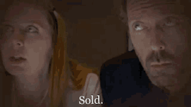 a man and a woman are standing next to each other and the woman is saying sold .