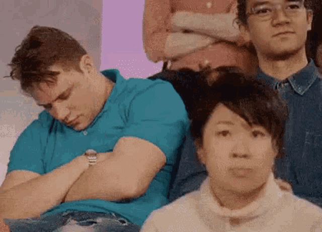 a group of people are sitting in a row and one of them is sleeping on another person 's lap .