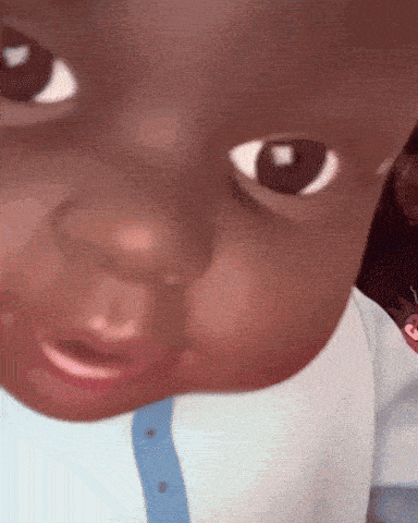 a close up of a baby 's face with a blue shirt on