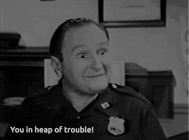 a black and white photo of a man in a police uniform with the caption you in heap of trouble