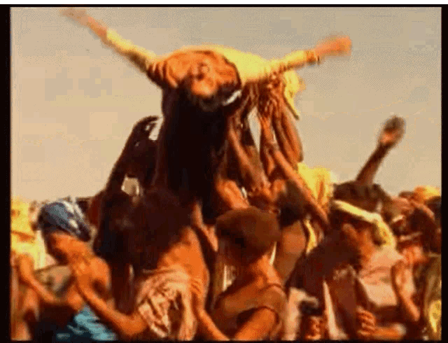 a group of people are standing in a crowd with a man standing on top of them