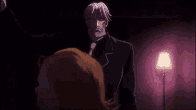 a man in a suit and tie is standing next to a woman in a dark room .