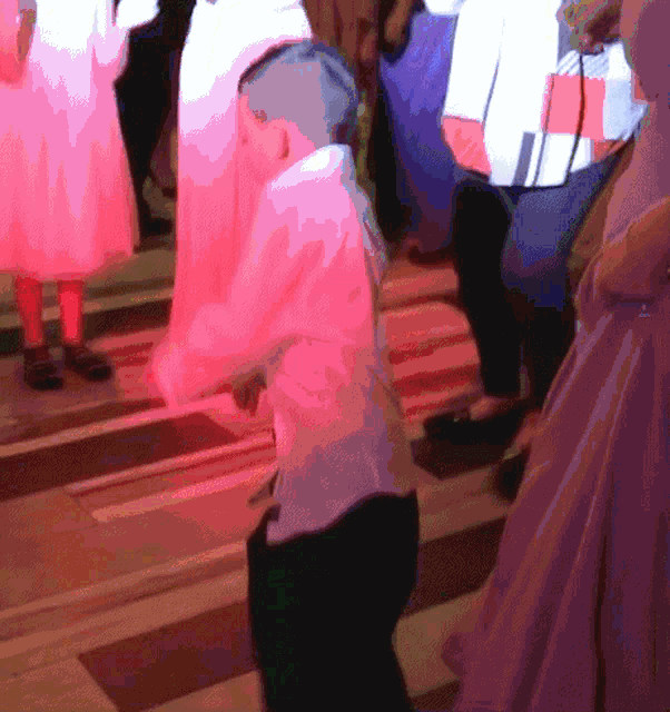 a boy in a white shirt is dancing in front of a crowd of people
