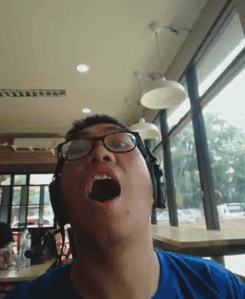 a man wearing glasses and headphones is yawning