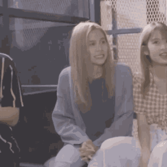 a group of young women are sitting next to each other in a room and smiling .