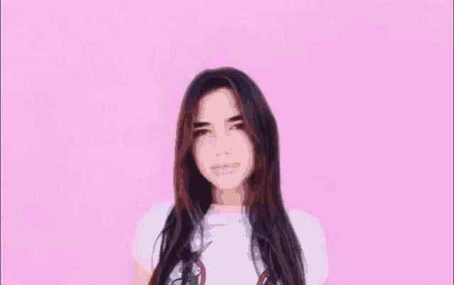 a woman wearing a unicorn shirt is smiling with her eyes closed against a pink background .