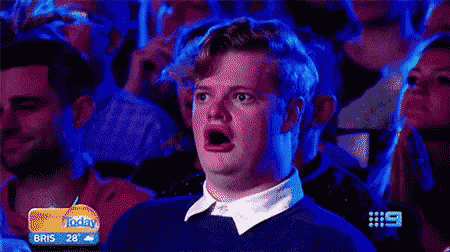 a man is making a surprised face in front of a crowd .