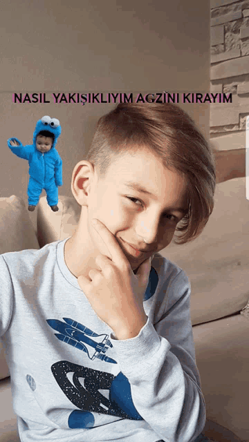 a young boy sitting on a couch with a baby in a cookie monster costume in the background