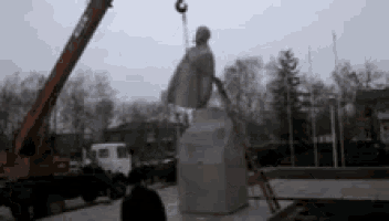 a statue is being lifted by a crane in a park .